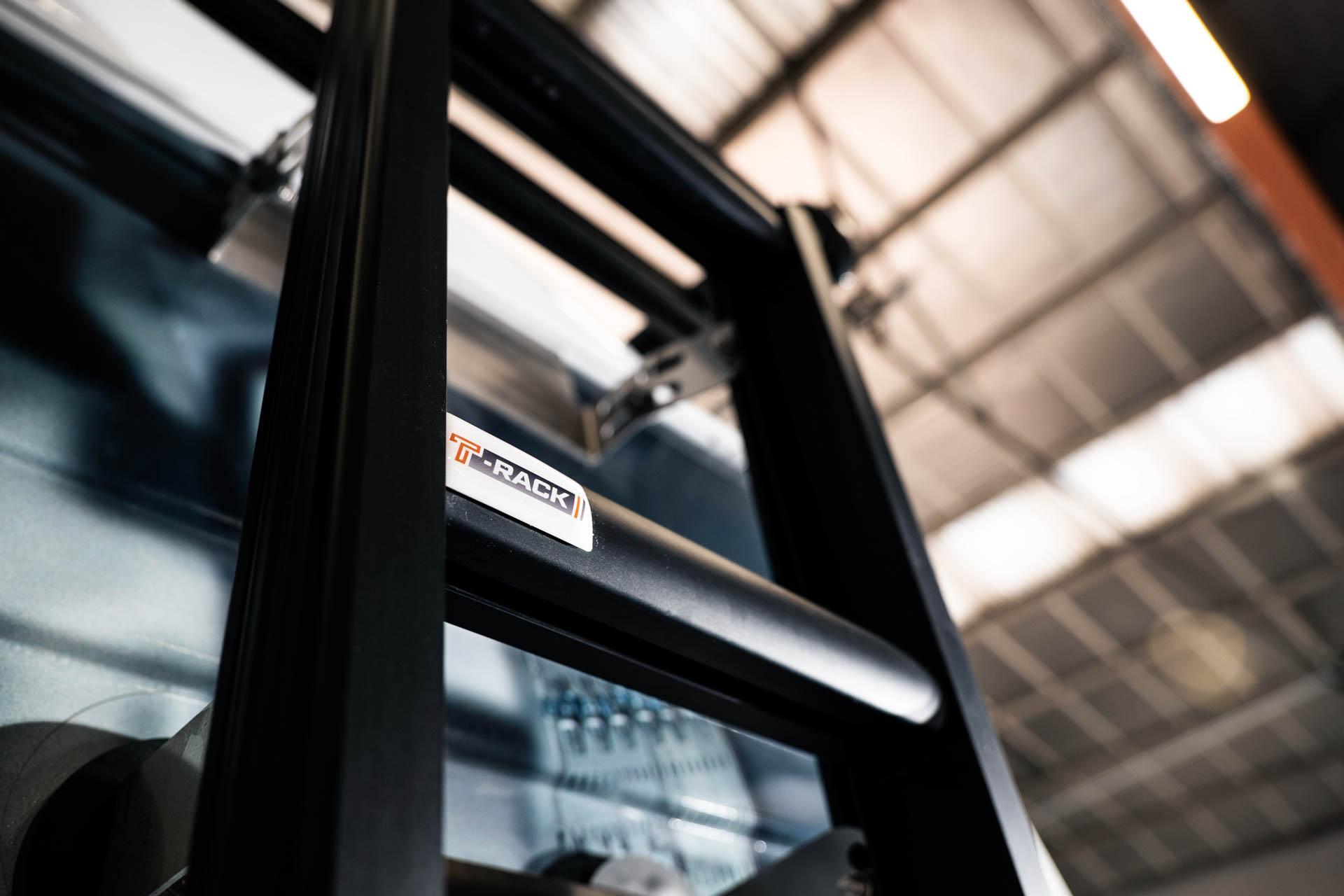 Een zwarte T-RACK ladder gemonteerd achteraan op een bestelwagen